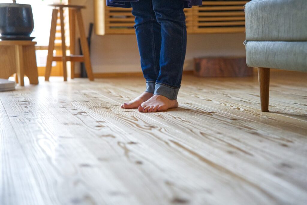 無垢材の床の上に裸足で立っている女性の足元