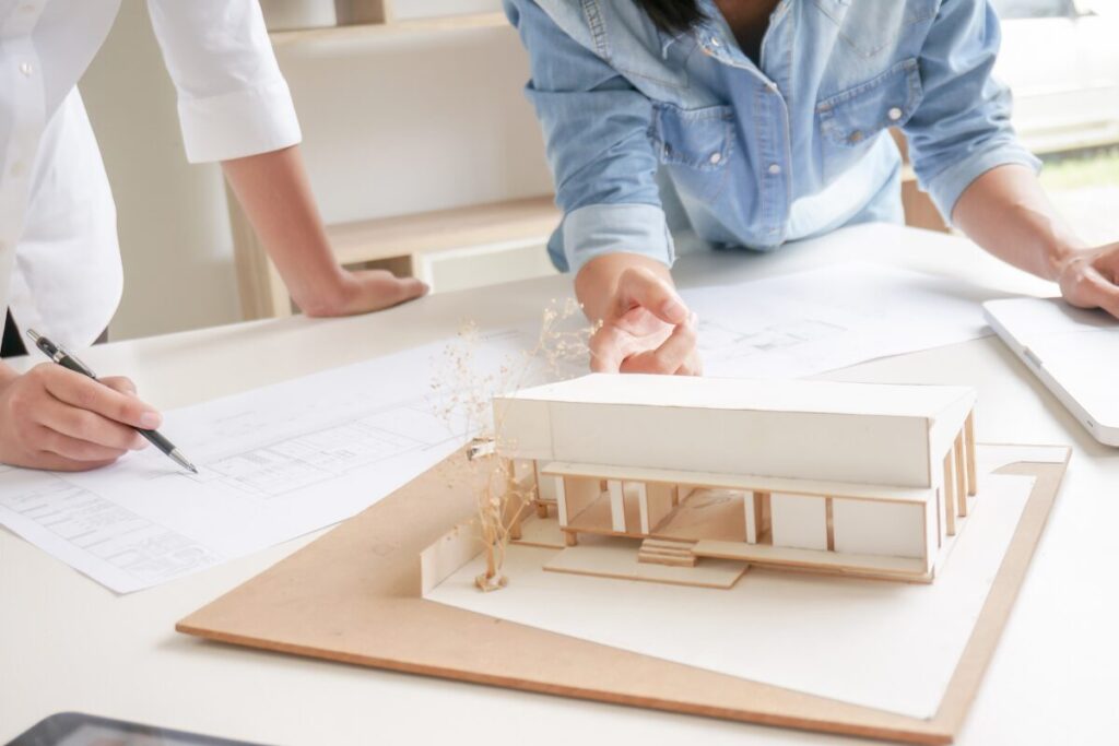 家の模型をみながら打ち合わせをする建築士